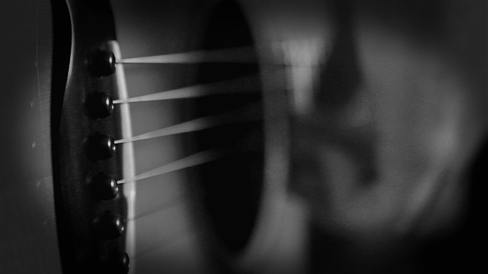 a close-up shot of a guitar and link to the music video