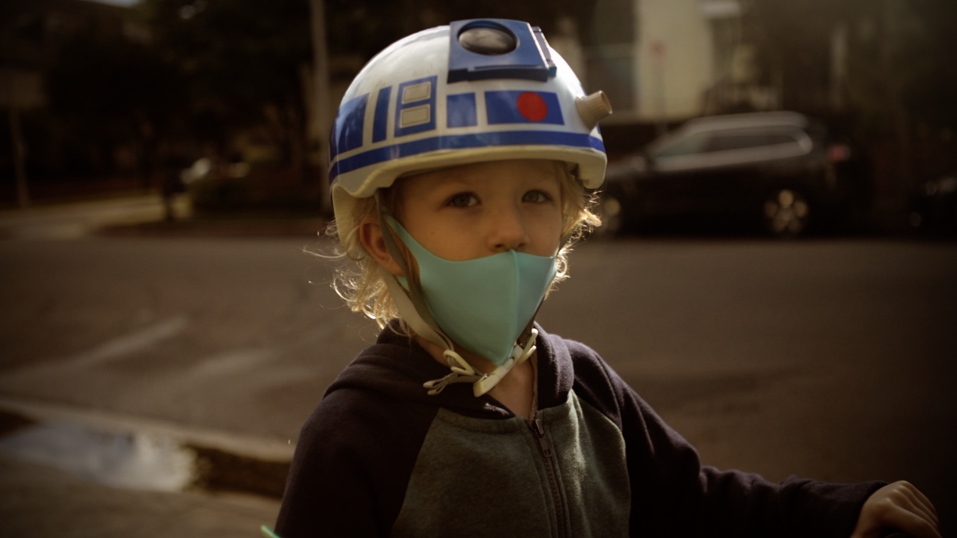 a boy with a bike helmet and a face mask on his bike