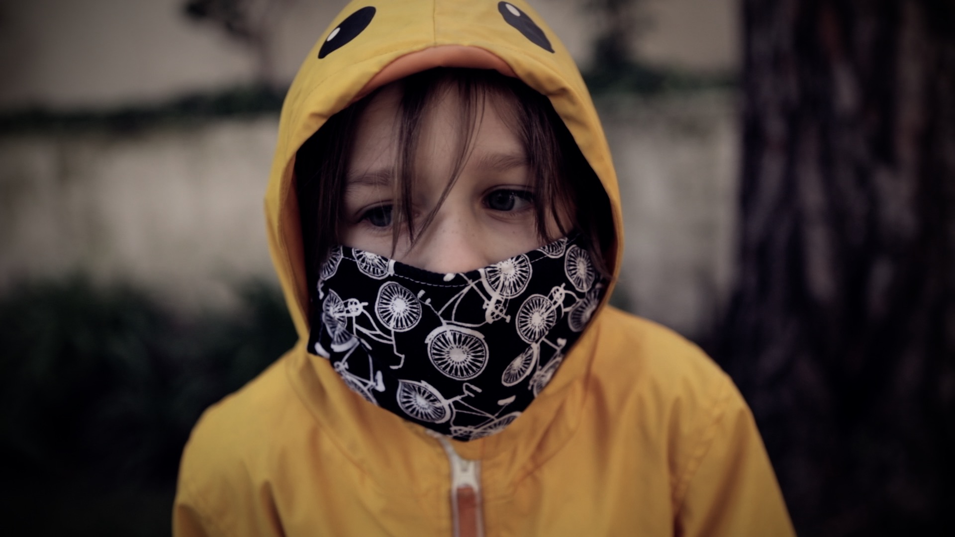 a boy in a raincoat wearing a face mask